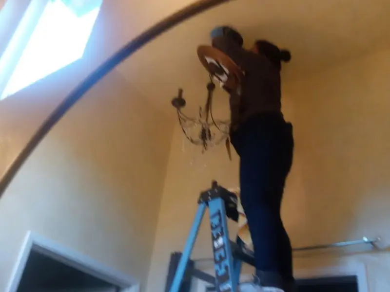 Electrician installing a chandelier in a Encinitas residence